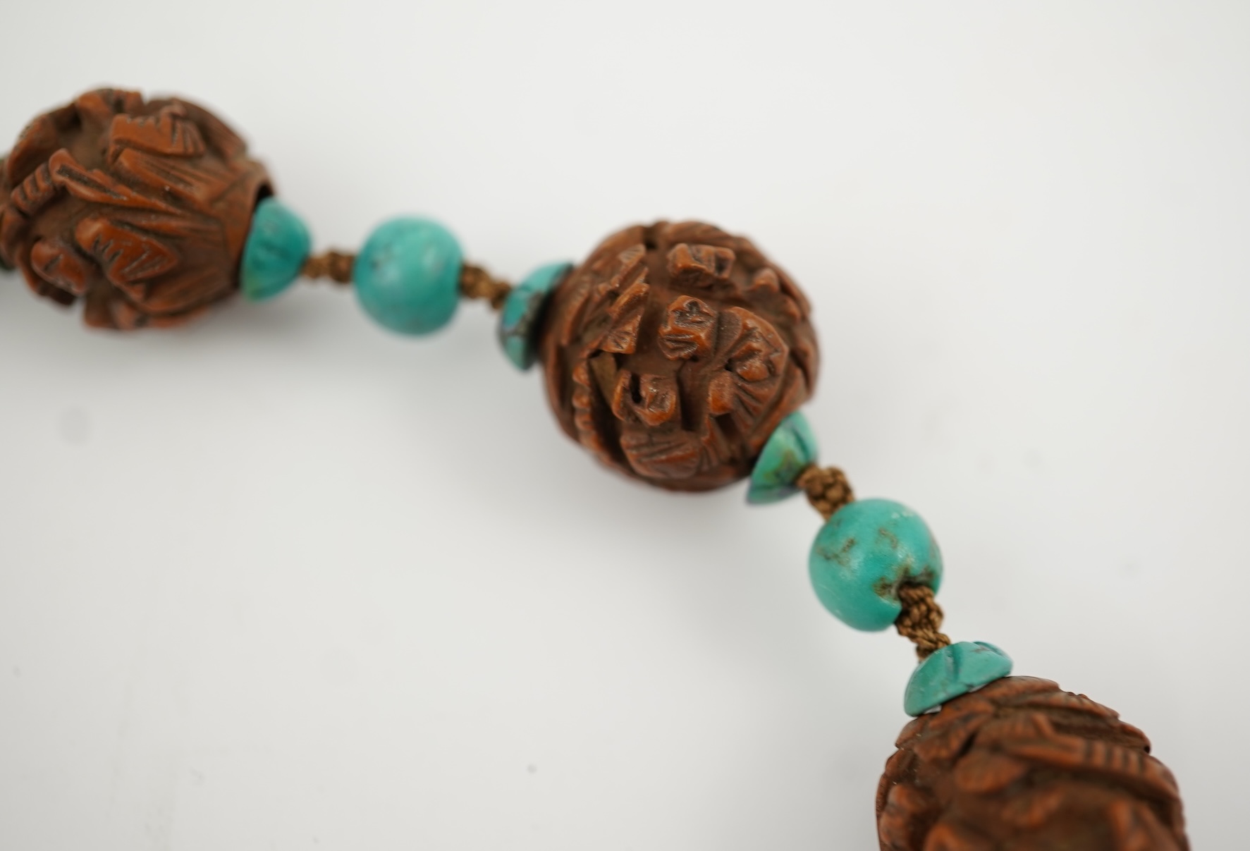 A Chinese silver filigree work and enamel scent bottle, by Wongshing, three carved peach stones, and a kernel and turquoise bead necklace, late 19/early 20th century